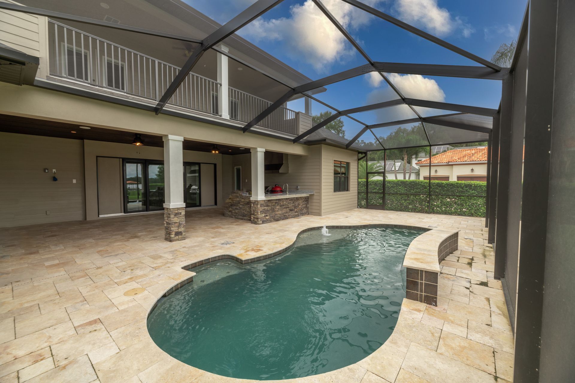Backyard with pool, screened-in patio, second-story balcony. Tan tiling, blue water, beige walls, blue sky.