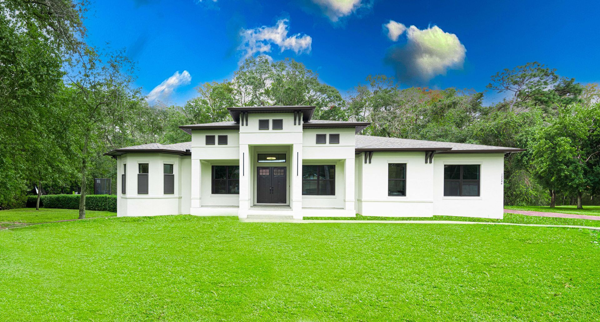 White house with dark windows, a dark front door, and a green lawn, under a blue sky.
