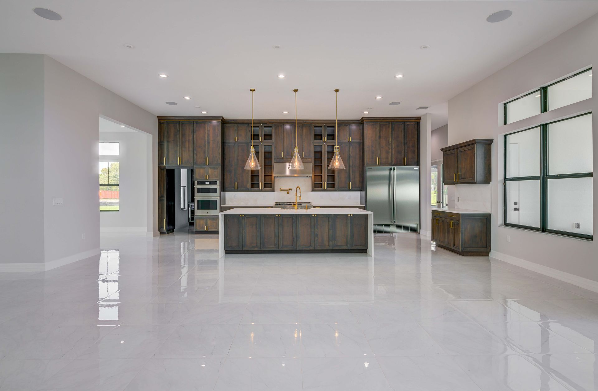Modern kitchen with dark wood cabinets, white countertops, and stainless steel appliances.