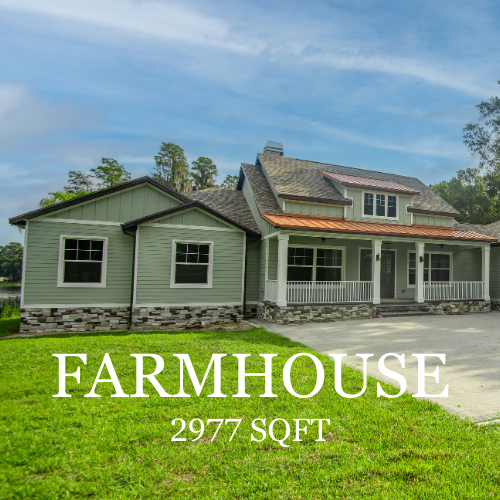 Farmhouse with green siding, brick foundation, and covered porch; grassy lawn in front, sunny day.