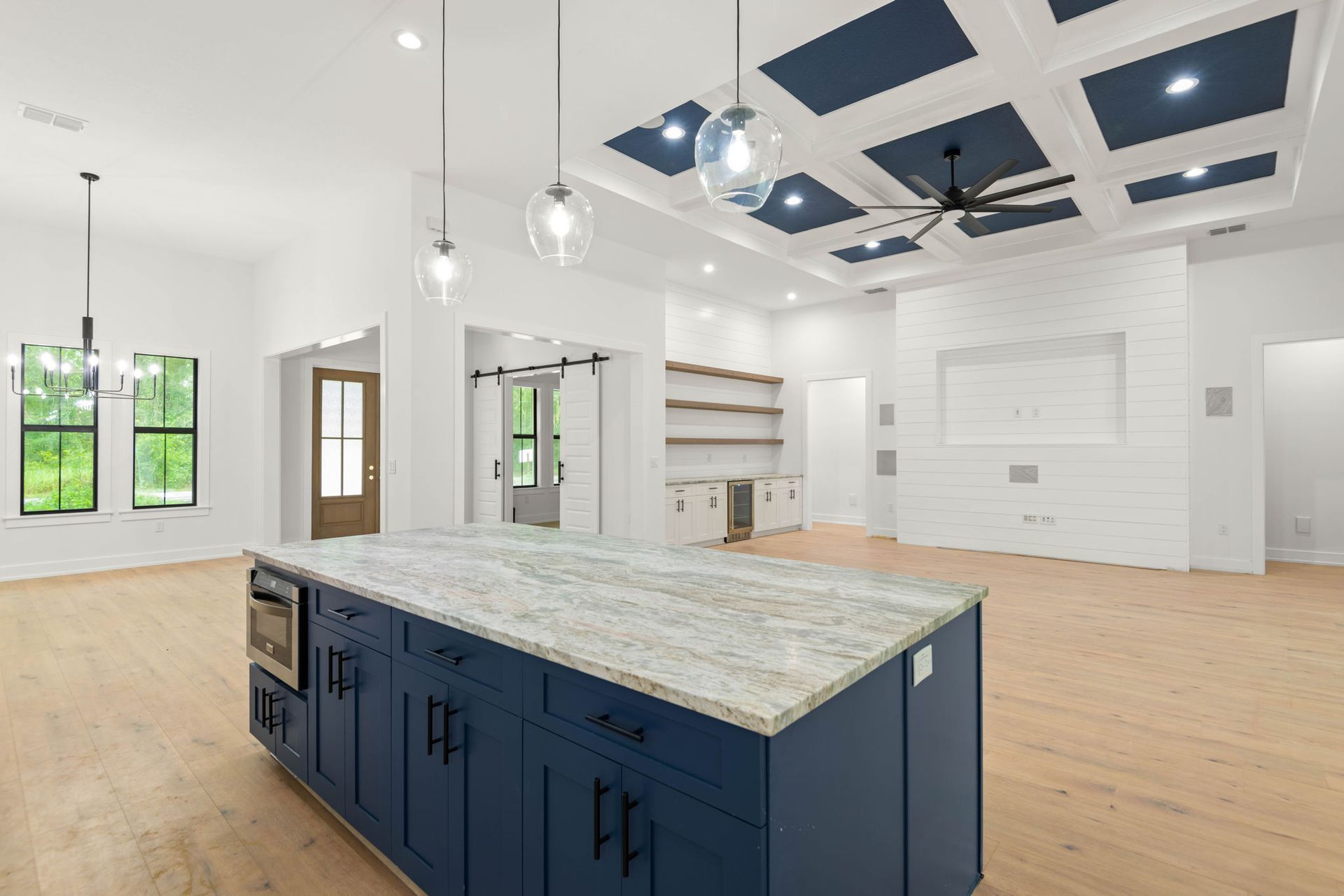 Modern kitchen with navy blue island, white walls, and coffered ceiling.