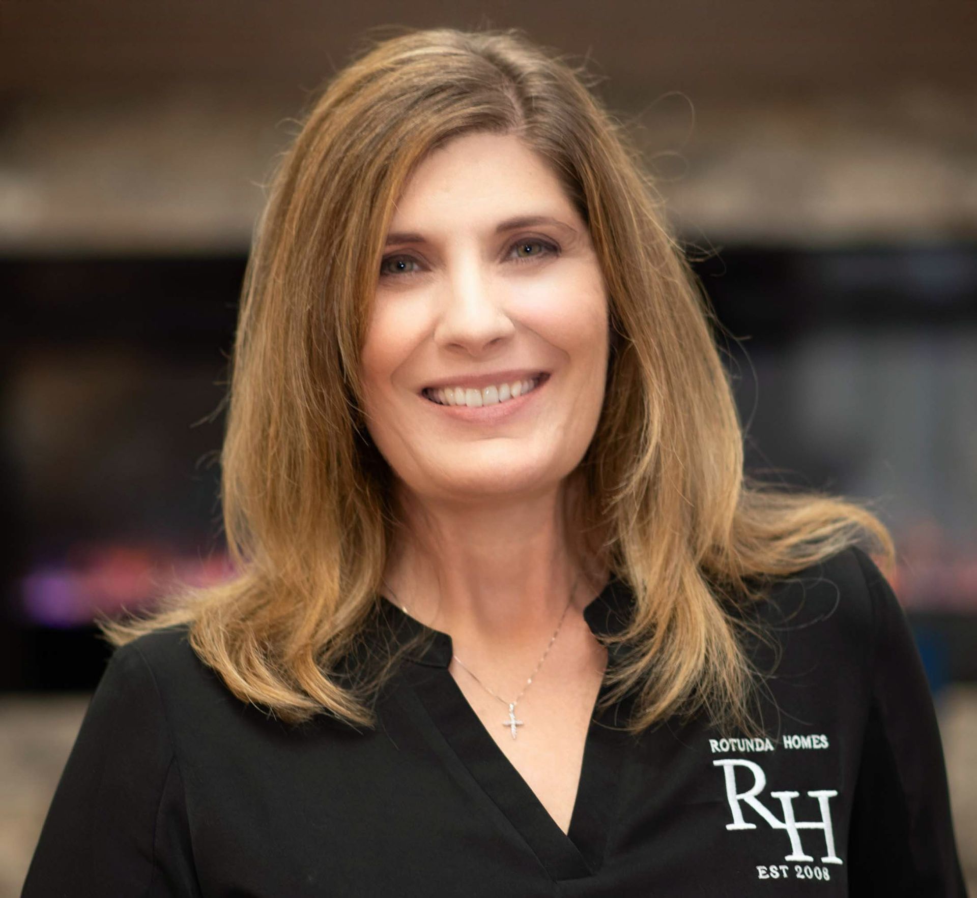 Woman with blonde hair wearing a black shirt with embroidered