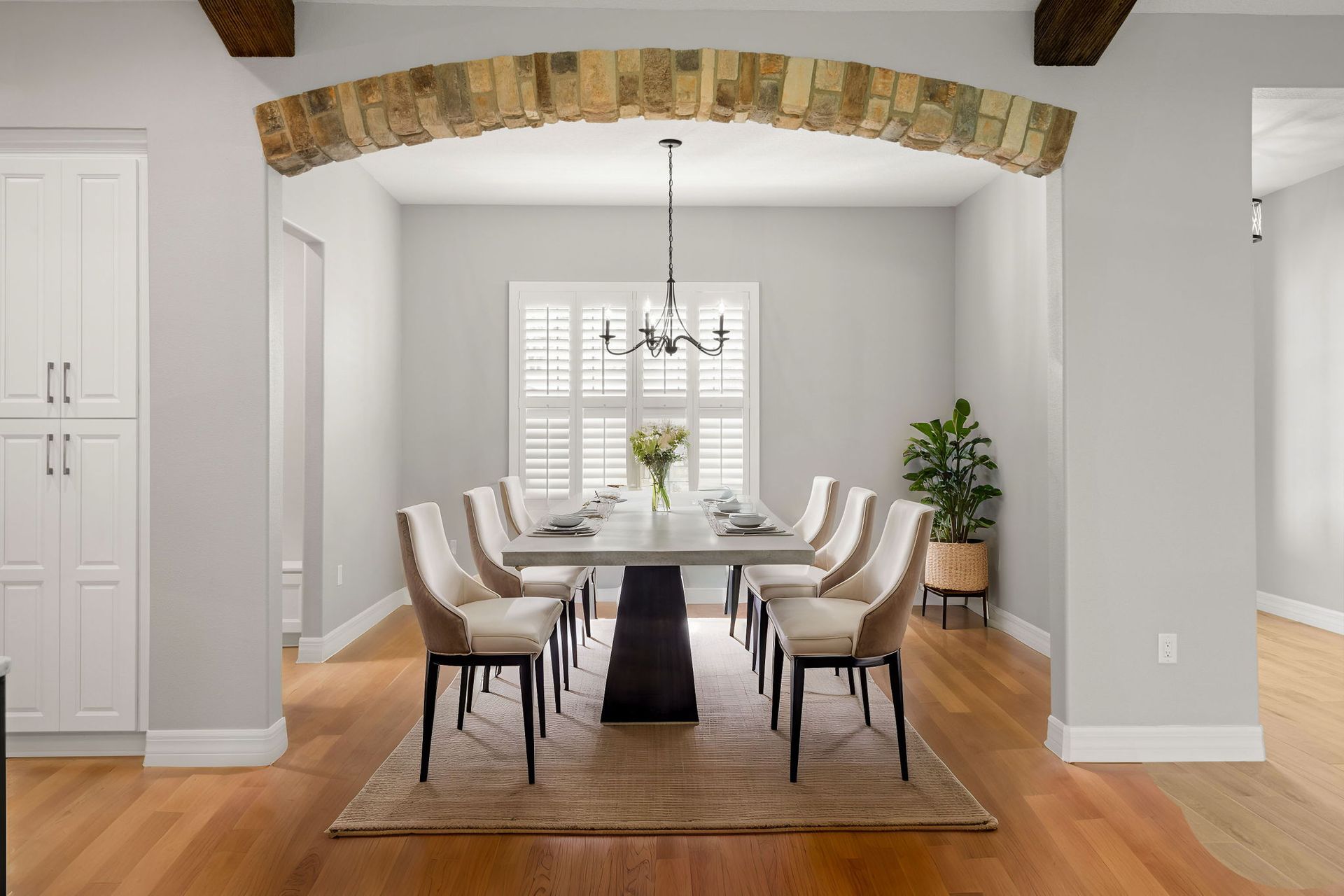 Dining room with a long table, chairs, and a decorative stone archway.