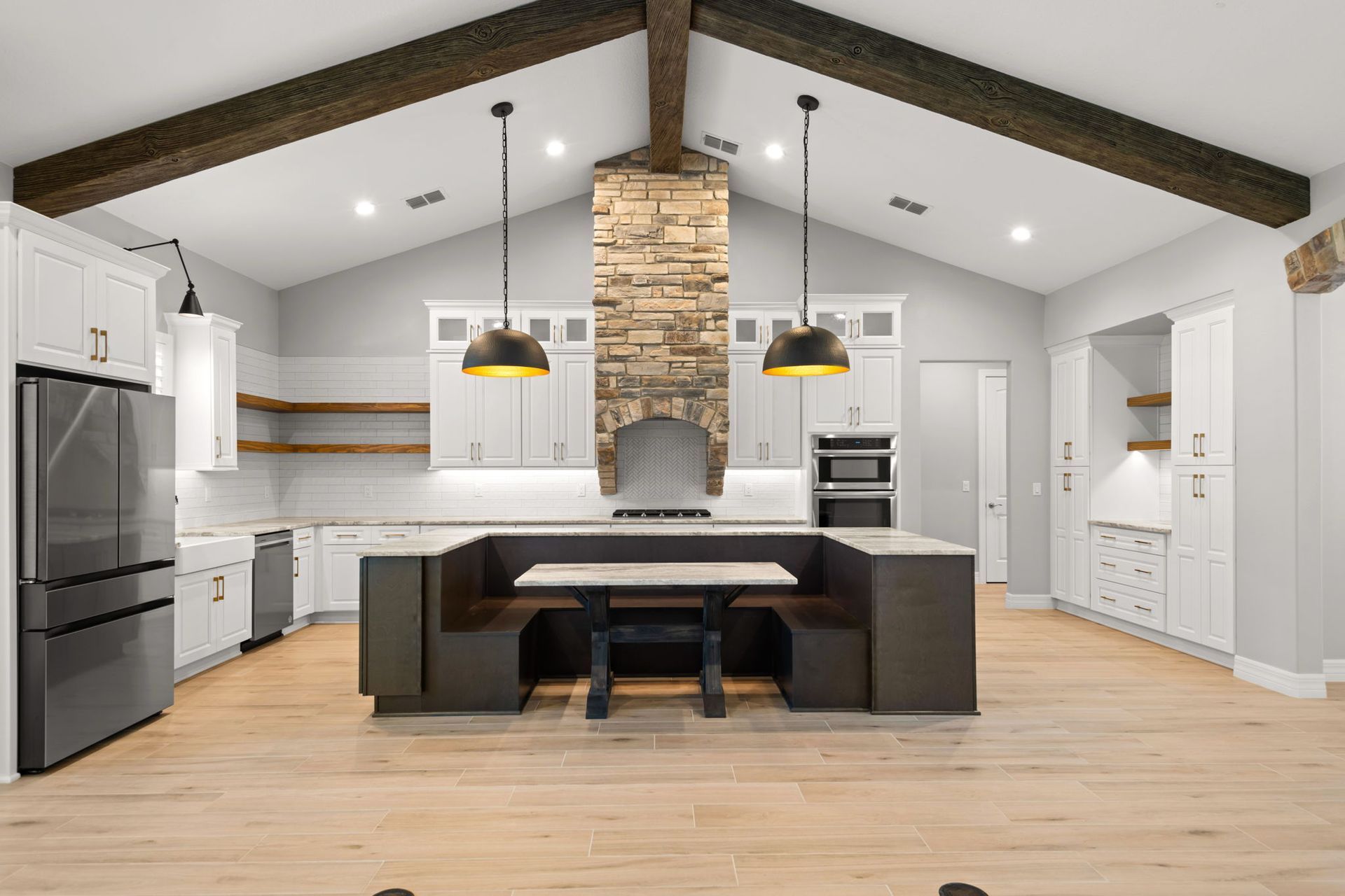 Spacious kitchen with wood beams, white cabinets, and a dark brown built-in booth.