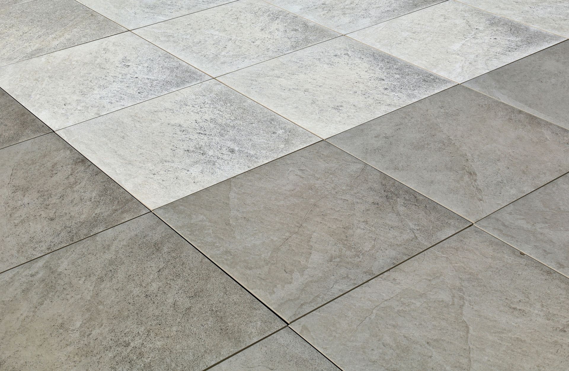 Motivo geometrico a piastrelle con alternanza di forme a rombi grigio chiaro e grigio scuro.