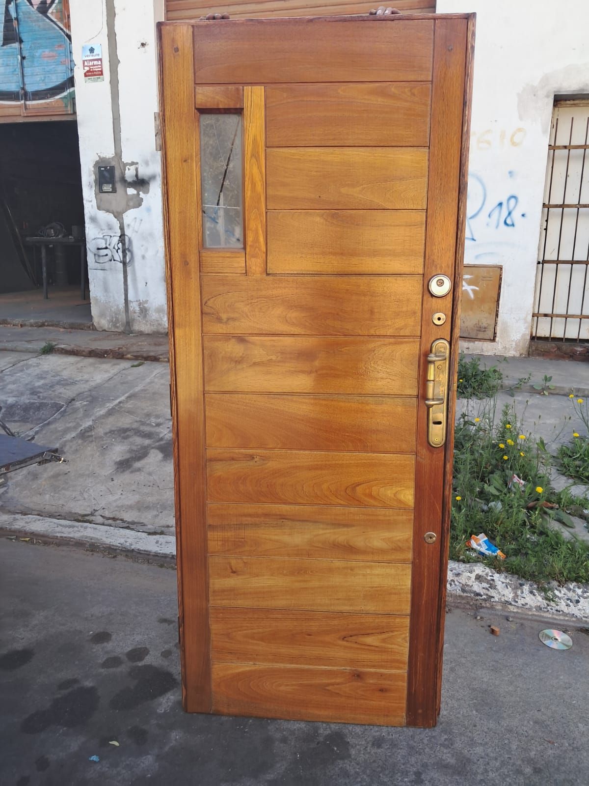 Puerta de entrada de madera con un estrecho panel de vidrio, situada en el exterior de un edificio en una calle.