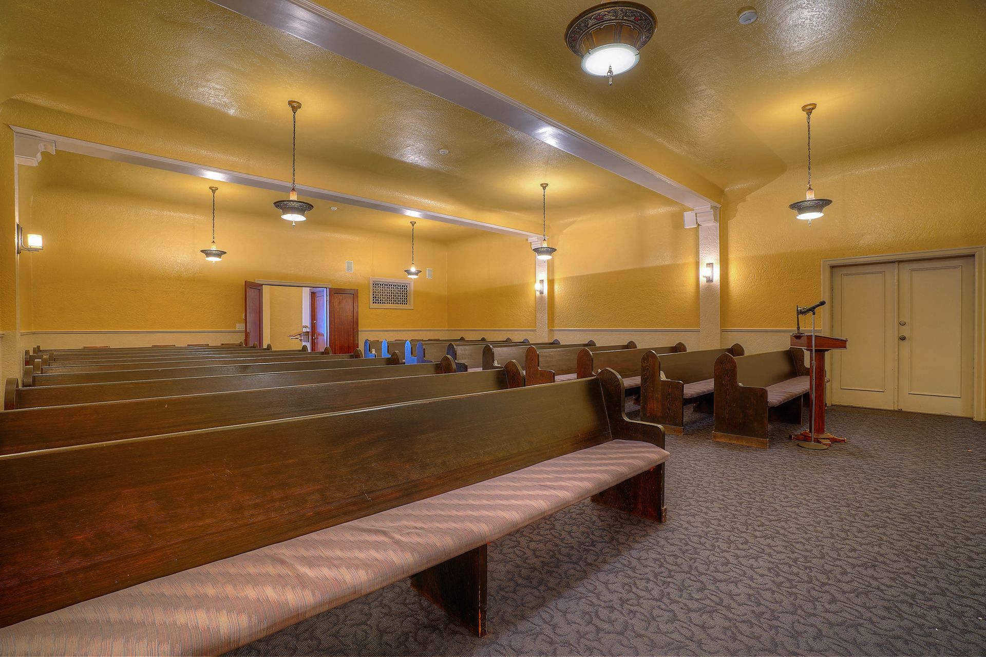 An empty church with rows of benches and a podium.
