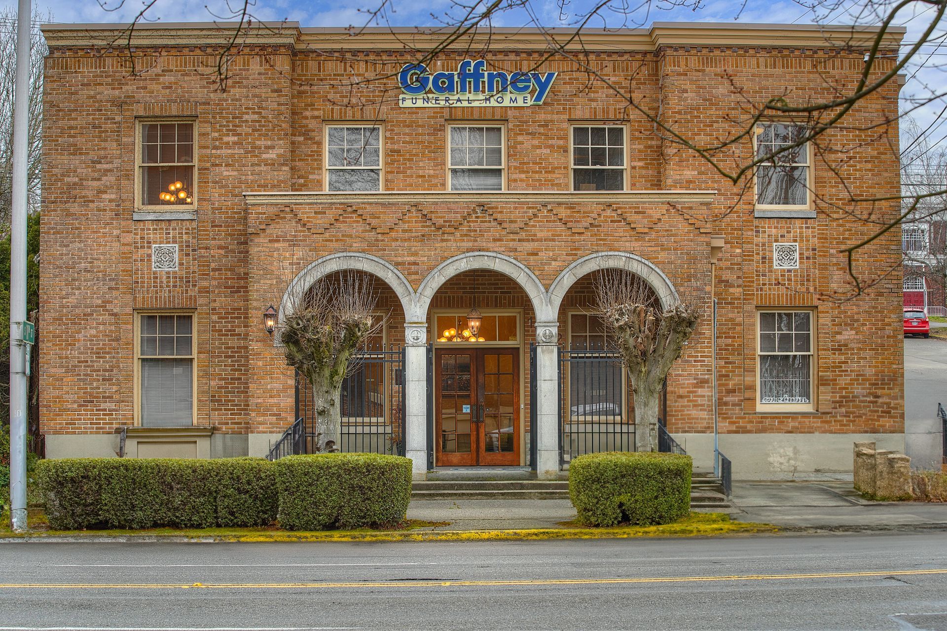 Brick storefront with arched entrance and blue sign above the door on a rainy street