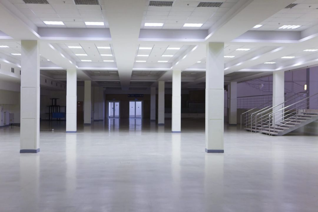 A large empty room with columns and stairs in a building.