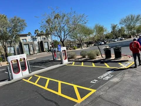 A parking lot with a tesla charging station in the background