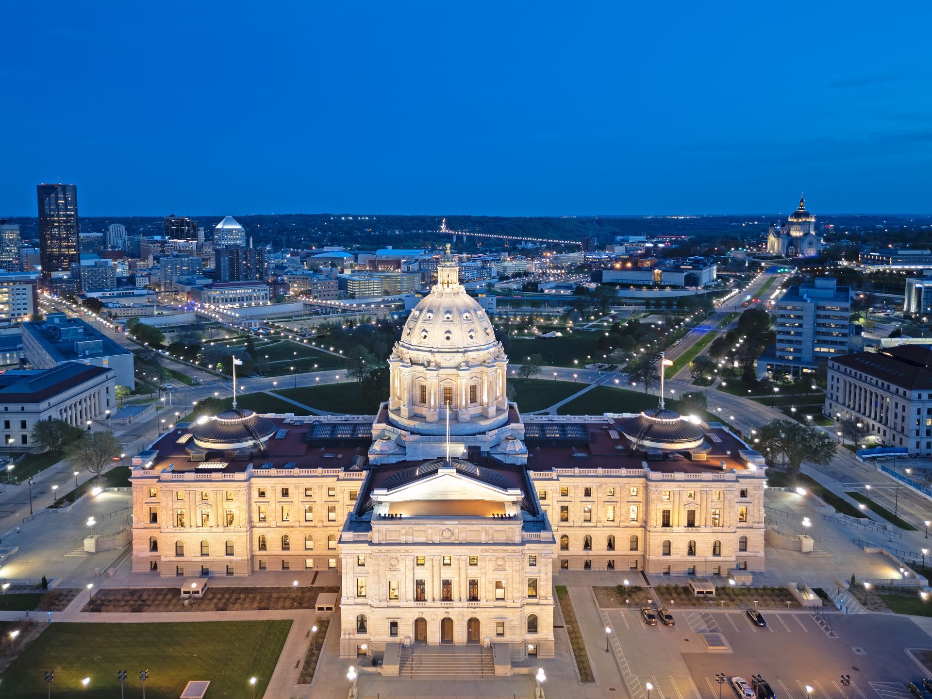Night view of a lit government building with a domed center, seen from above in a cityscape