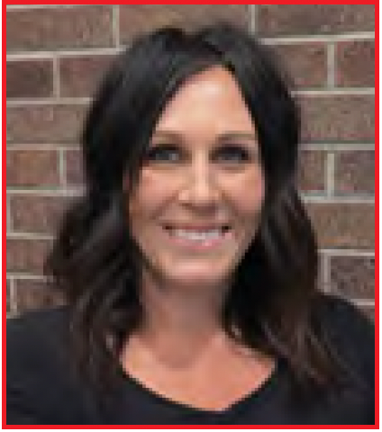 Woman with dark hair smiling in front of a brick wall.