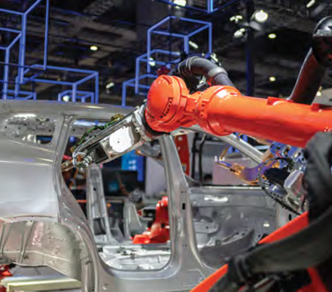 Industrial robot arms assembling a silver car body on a factory line