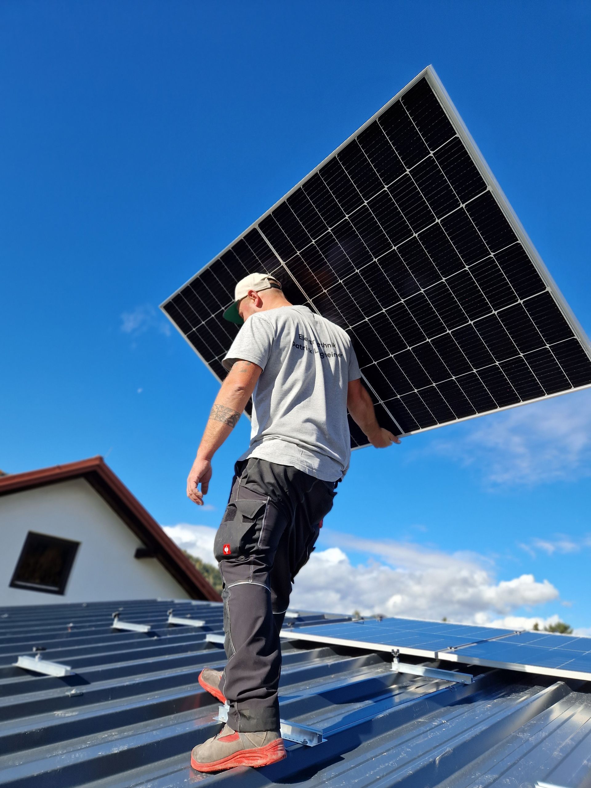 ein mann steht auf einem dach und trägt ein solarpanel