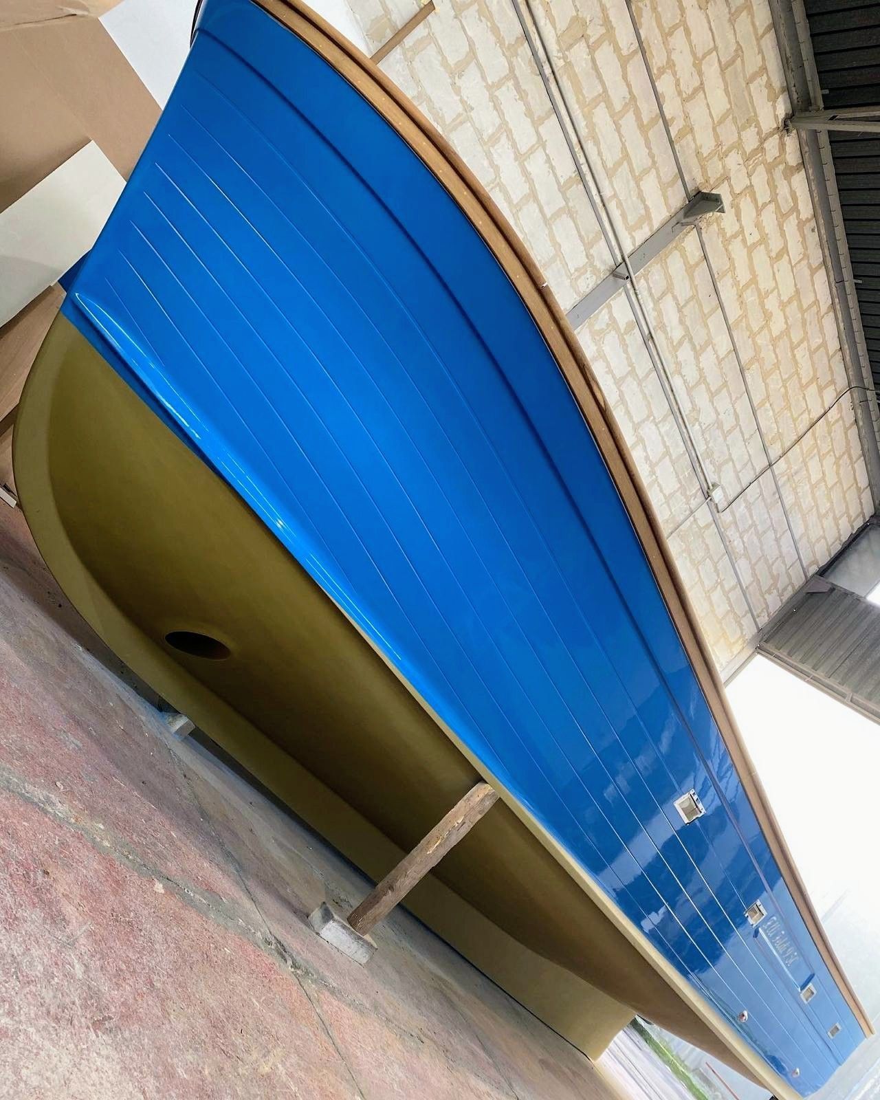 Una veduta grandangolare dello scafo di una barca in vetroresina in costruzione, che mostra la sua struttura interna a griglia e l'intelaiatura di supporto.