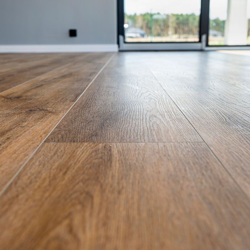 Empty modern room with wood-look flooring and a glass door to a bright outdoor view