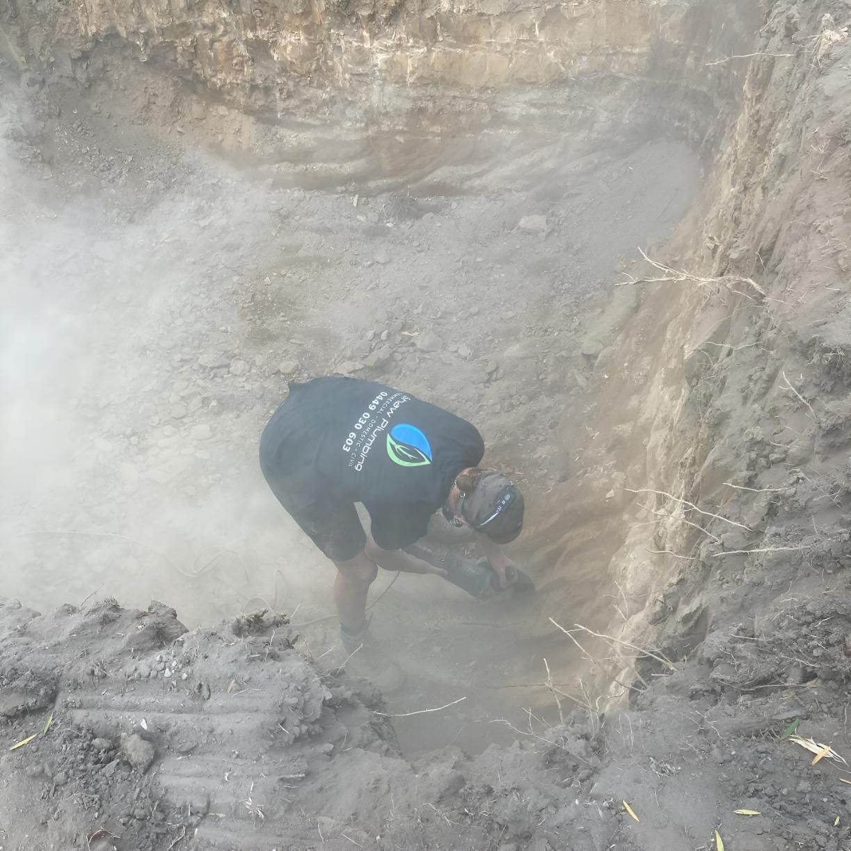 A Man in a Black Shirt is Digging a Hole in the Dirt — Shawline Plumbing and Drainage In Maclean, NSW