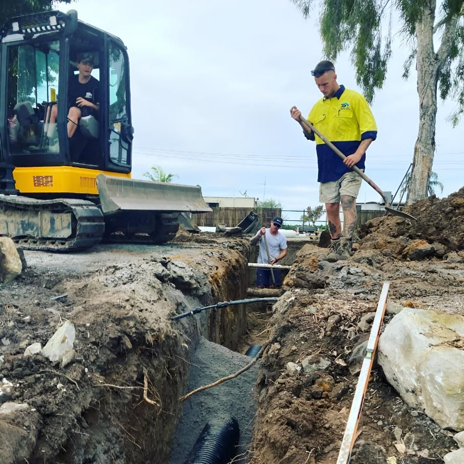 Two Men Are Digging in the Dirt Near a Bulldozer — Shawline Plumbing and Drainage In Iluka, NSW