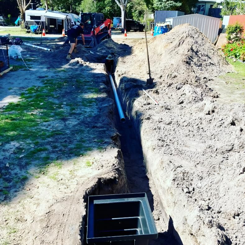 A Man is Digging a Hole in the Ground to Install a Pipe — Shawline Plumbing and Drainage In Iluka, NSW