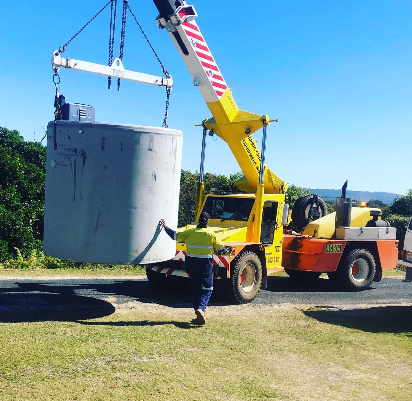 A Man is Standing Next to a Large Green Container in the Dirt — Shawline Plumbing and Drainage In Iluka, NSW