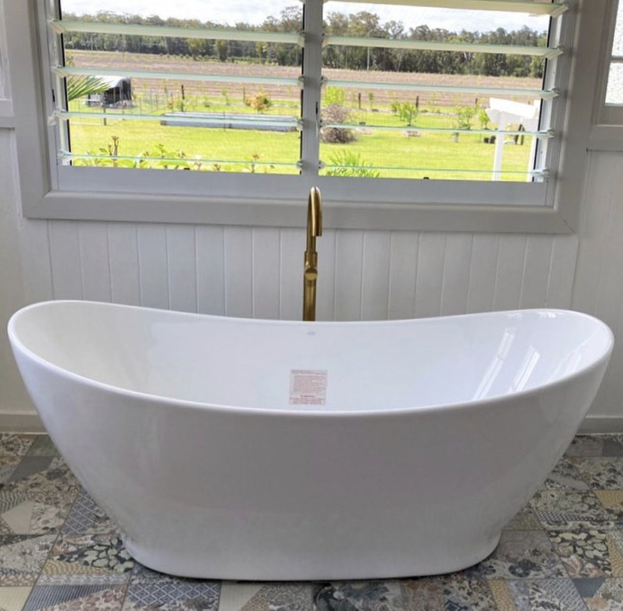 A White Bathtub is Sitting in a Bathroom Next to a Window — Shawline Plumbing and Drainage In Iluka, NSW