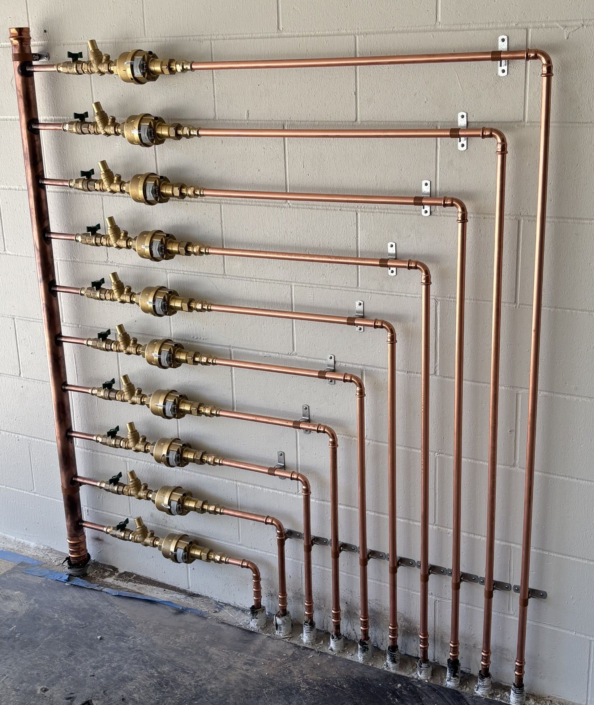 a set of gold meter pipes in front of a wall in a garage — Shawline Plumbing and Drainage In Iluka, NSW
