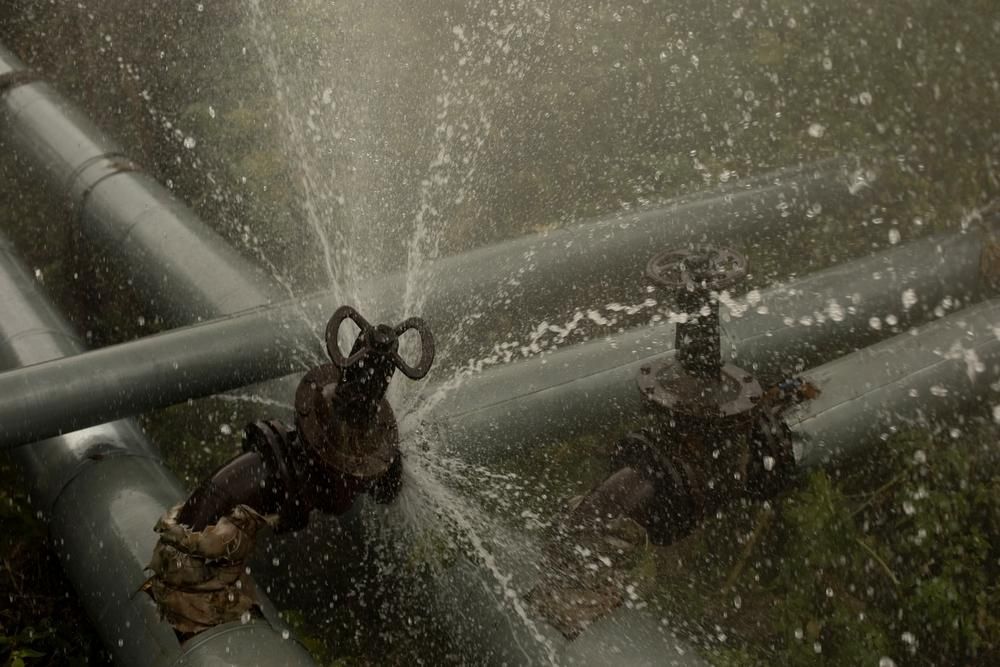 Water Gushes From a Rusty Valve on a Gray Pipe, Surrounded by Other Pipes in a Field — Shawline Plumbing and Drainage In Iluka, NSW