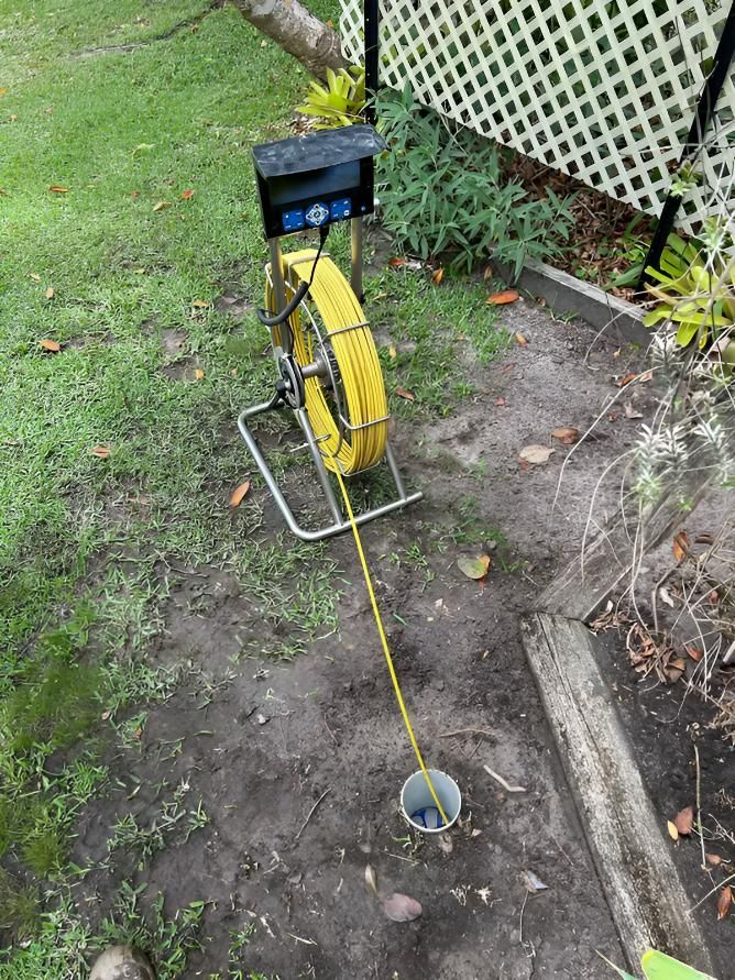 A Yellow Hose is Sitting on the Ground Next to a Fence — Shawline Plumbing and Drainage In Maclean, NSW