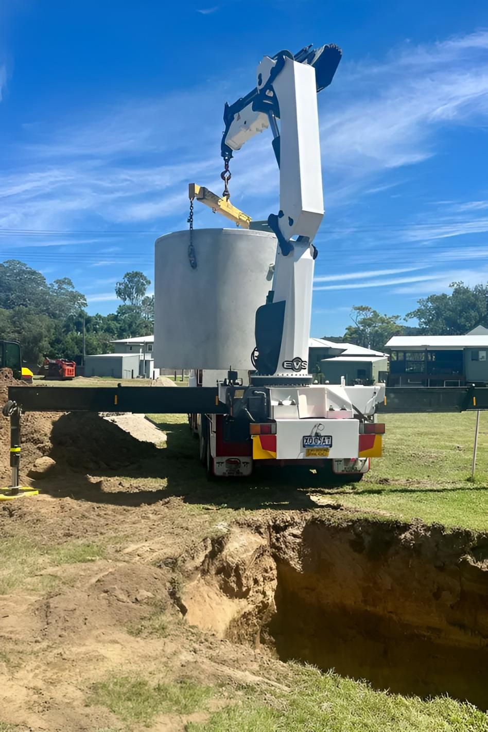 A Crane is Lifting a Large Concrete Cylinder Into a Hole in the Ground — Shawline Plumbing and Drainage In Maclean, NSW