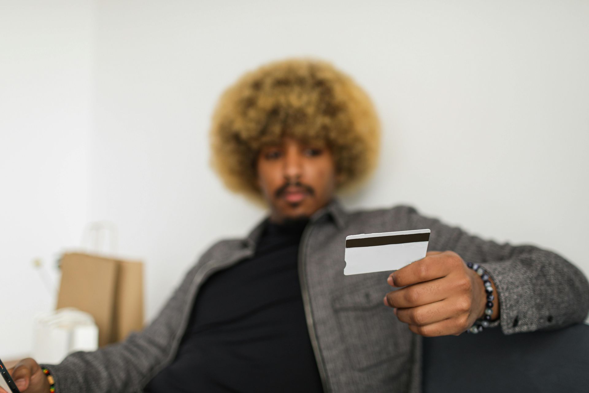 Man holding a credit card, looking at it in a bright room.