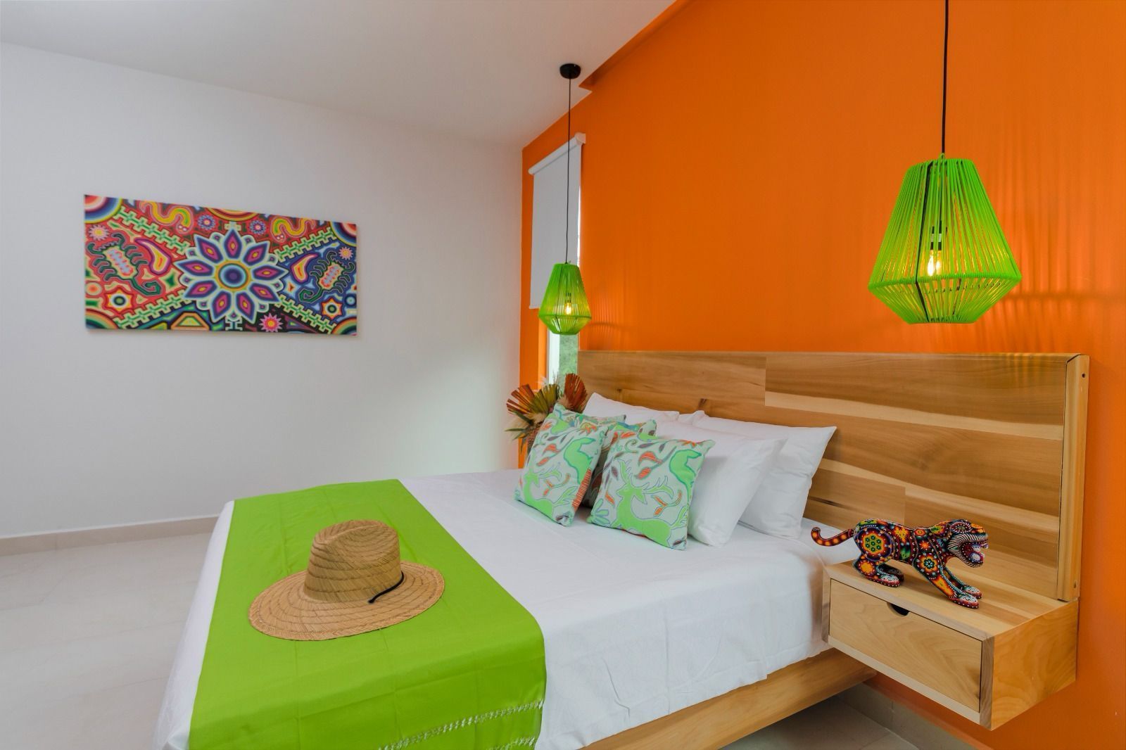 A bedroom with an orange wall and a bed with a green blanket and a hat on it.