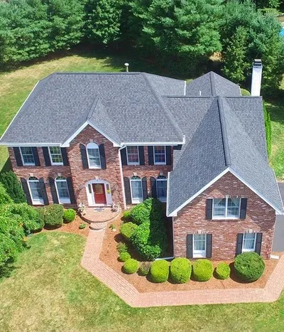 An aerial view of a large brick house with a gray roof