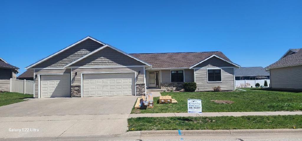 House with two garage doors and a lawn, under a clear blue sky. A 