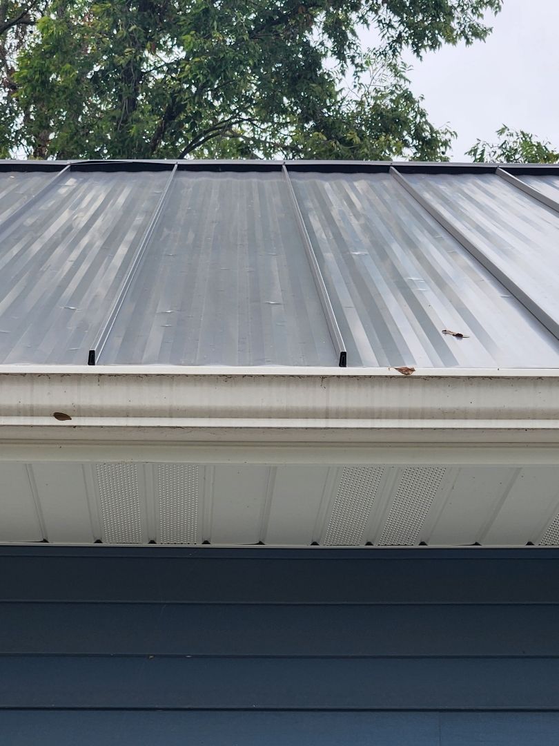 A close up of a metal roof with a white gutter on a house.