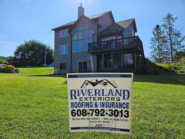A riverland exteriors roofing and insurance sign in front of a house — Holmen, WI — Riverland Exteriors Corporation