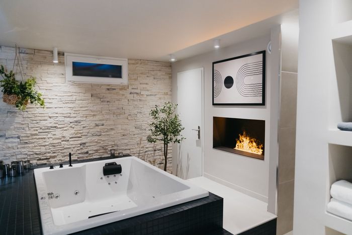 Une salle de bain avec baignoire jacuzzi et cheminée.