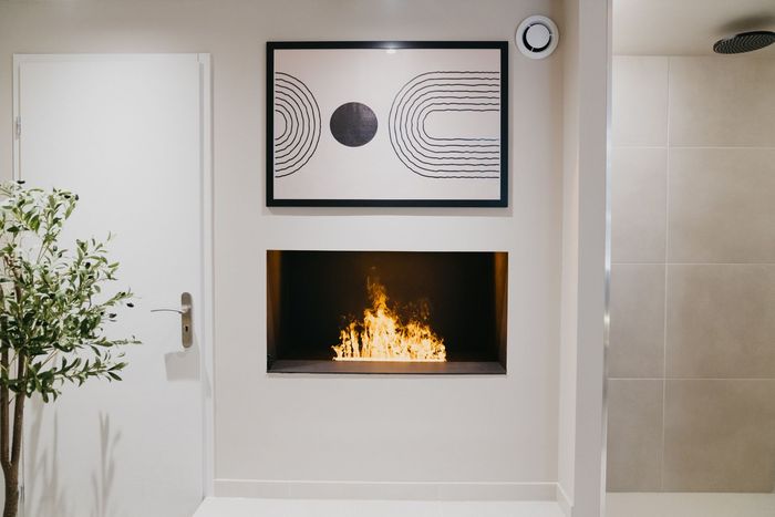 Il y a une cheminée dans le mur avec un tableau au-dessus.