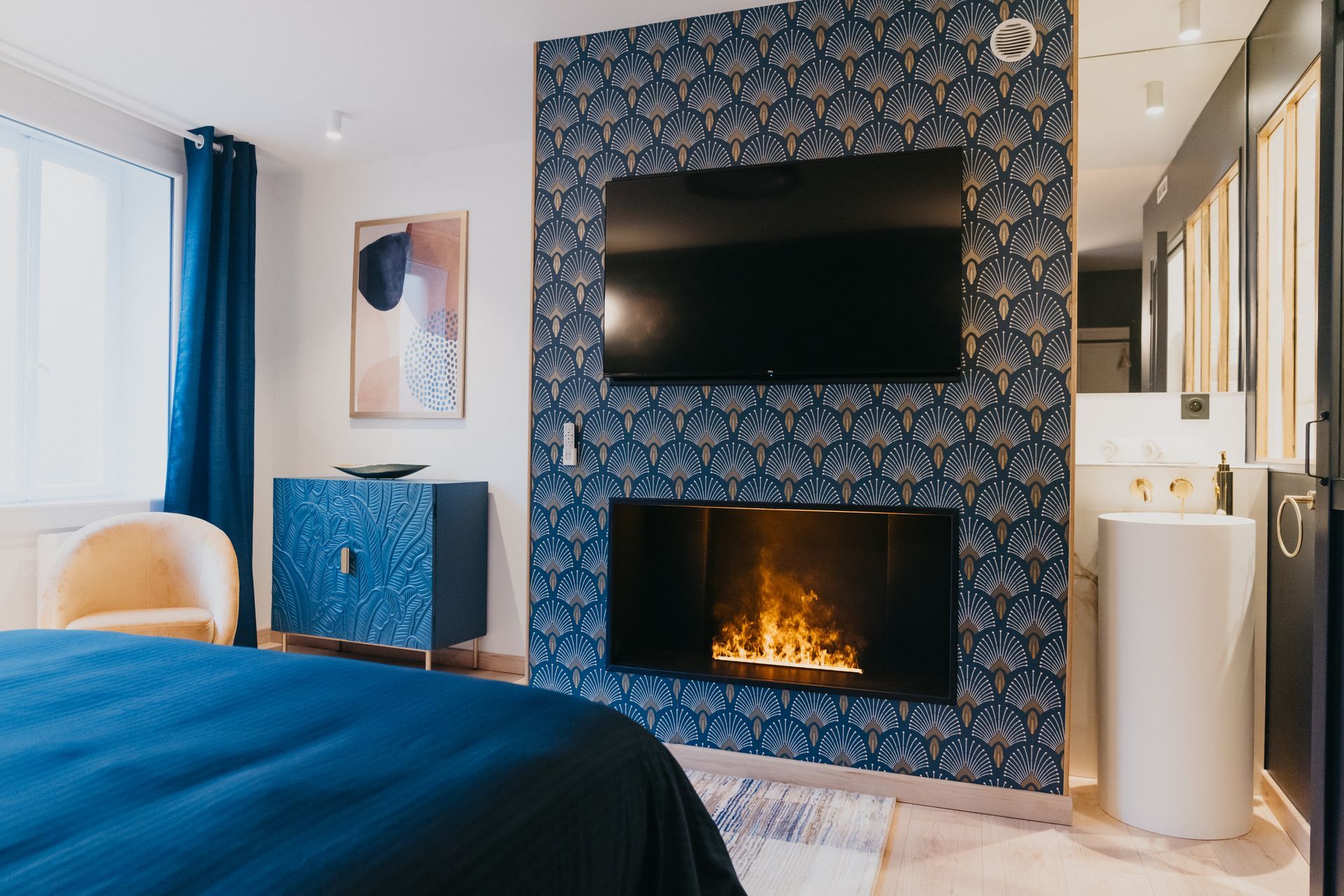 Une chambre avec cheminée, télévision et lavabo.