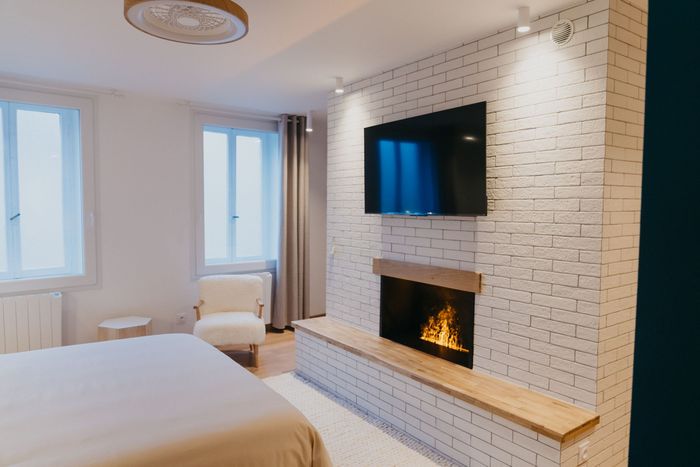 Une chambre avec une cheminée et une télévision à écran plat au mur.