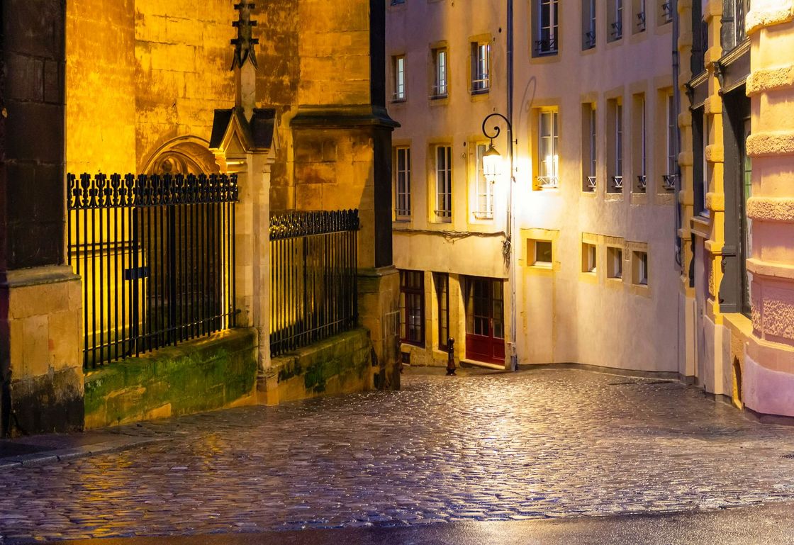 Une rue pavée avec un bâtiment en arrière-plan la nuit