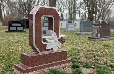 A gravestone with the letter o on it in a cemetery.
