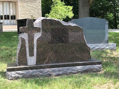 A gravestone with a cross on it in a cemetery.