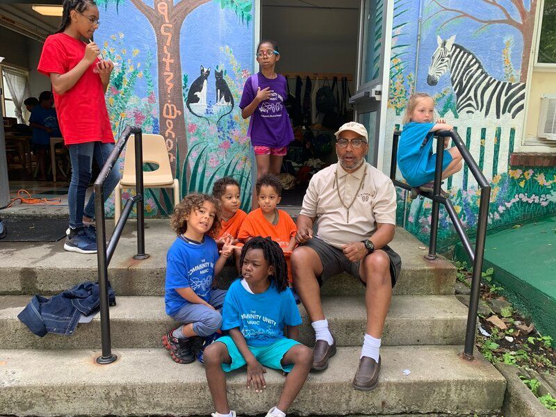 A group of children are sitting on the steps of a building.