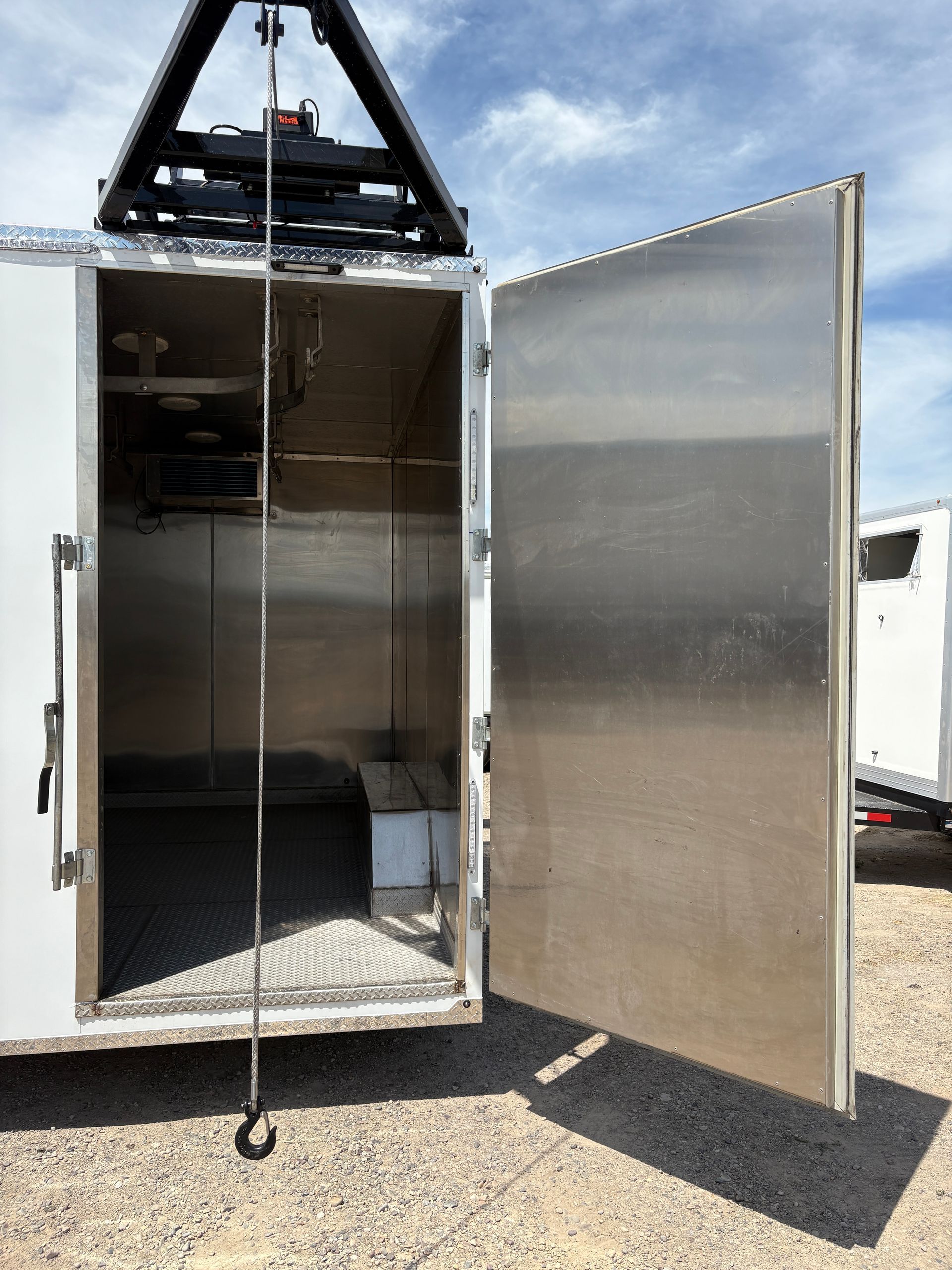 Open metal trailer with both doors ajar, showing an empty stainless steel interior.