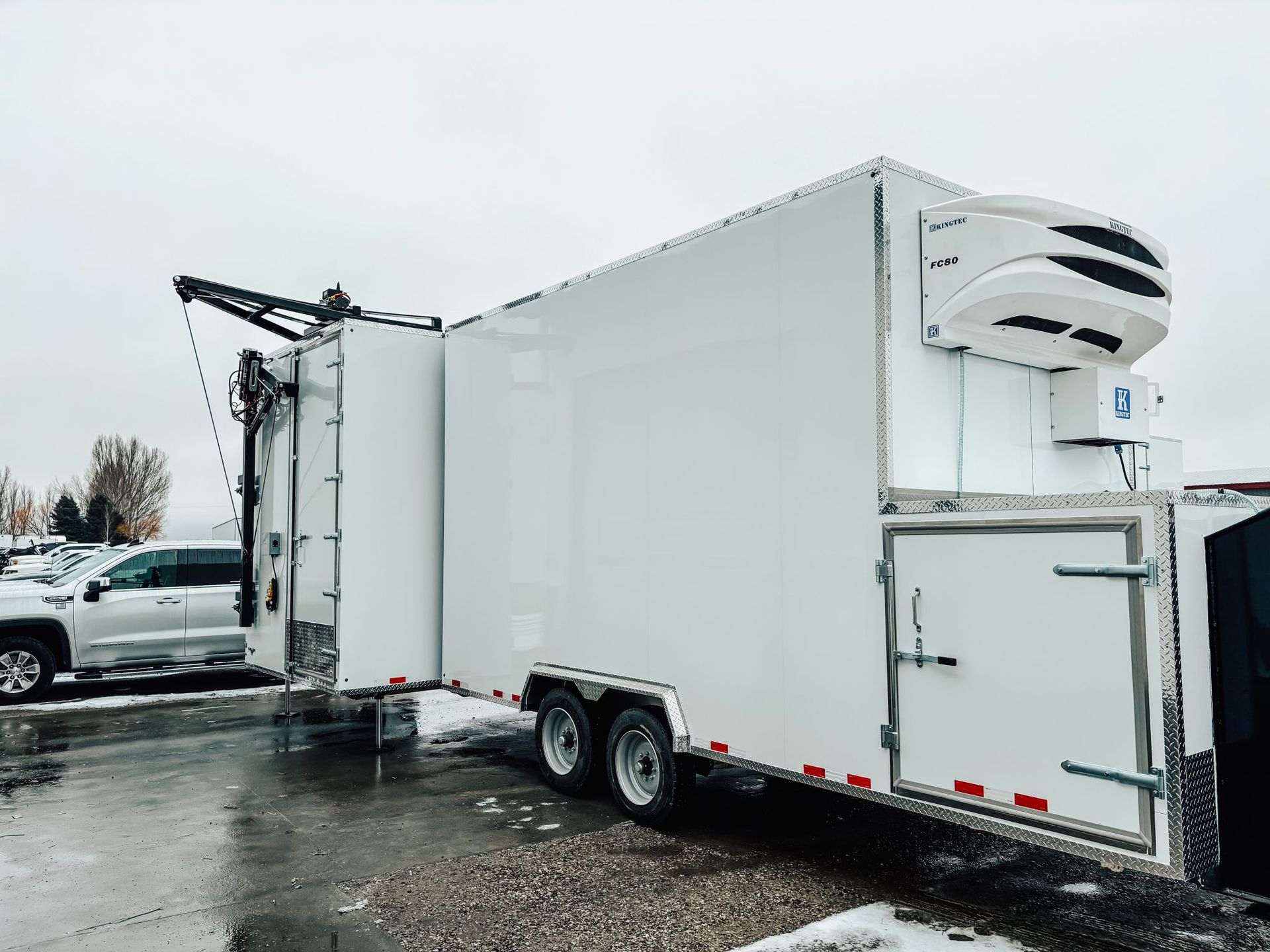 White refrigerated truck trailer parked in a snowy lot with a side door open