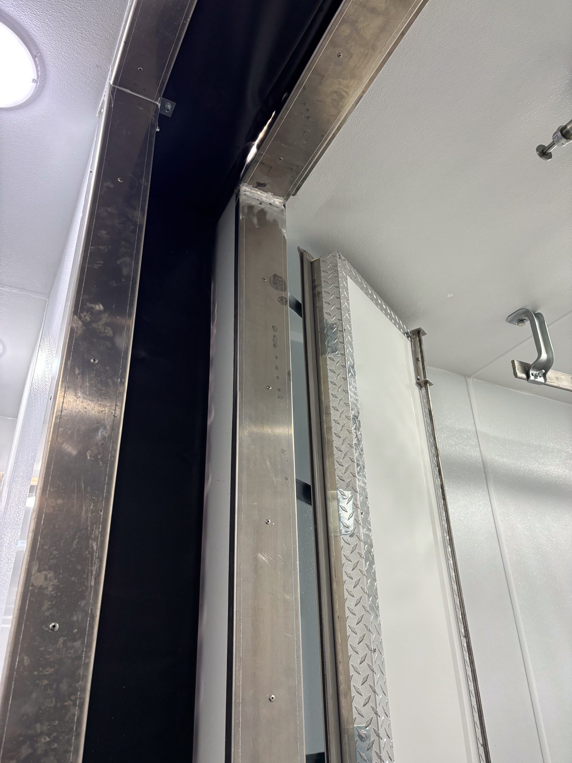 Close-up of a metallic door frame and hinge inside a meat processing trailer made by SEntinel Trailers
