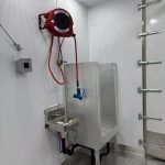 Red hose reel and metal safety shower station mounted on a Sentinel trailer wall