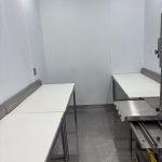 Small sterile room with two white tables against gray walls and tiled floor.