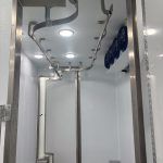 Interior of a Sentinel trailer with silver poles, white walls, and blue hanging straps under bright overhead lights