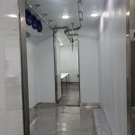 Narrow metal corridor with glossy walls inside a butcher trailer